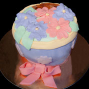 Torta scolpita a forma di vaso: base bianca e farcitura di crema pasticcera decorazioni e copertura in pasta di zucchero.