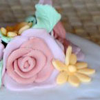Particolare, torta di rose: base bianca con crema pasticcera, copertura e decorazione con pasta di zucchero.